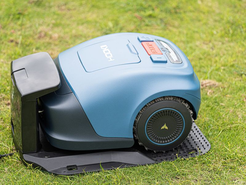 Wire-free robot mower parked on its charging station on a lawn