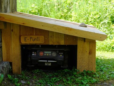 Robot mower parked inside a wooden mower garage at the edge of a lawn